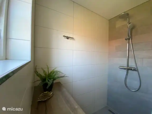 De badkamer is voorzien van een inloopdouche met regendouche.